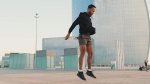 Fit and healthy aging man performing squat jumps in the city center
