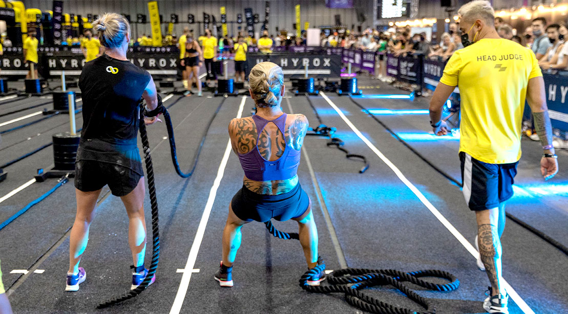 Fit female competitors performing sled pulls in a Hyrox competition