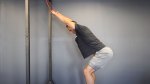Fit man performing the The Straight Arm Press Down With Hinge using resistance bands tied to a rack
