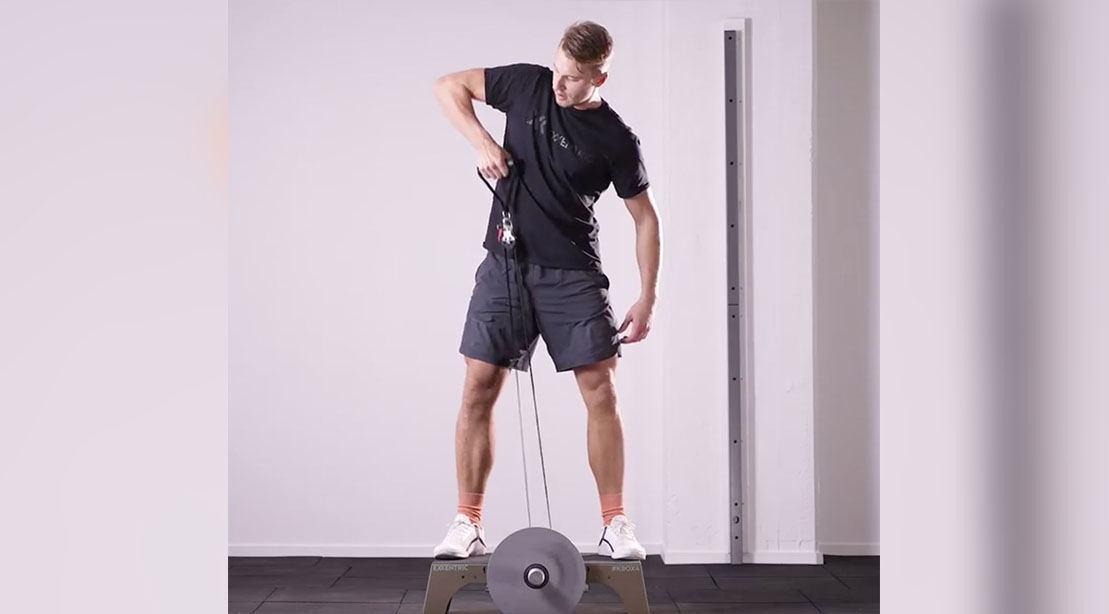 Fit tall blonde man performing a flywheel training exercise