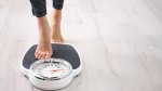 Fit woman stepping on the scale to measure her weight loss progression