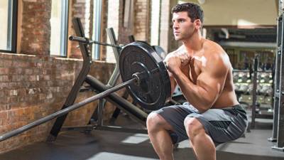 Muscular man performing a landmine training with a landmine squat exercise