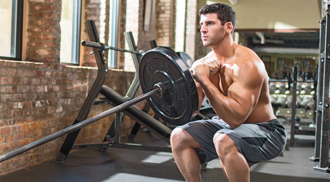 Muscular man performing a landmine training with a landmine squat exercise