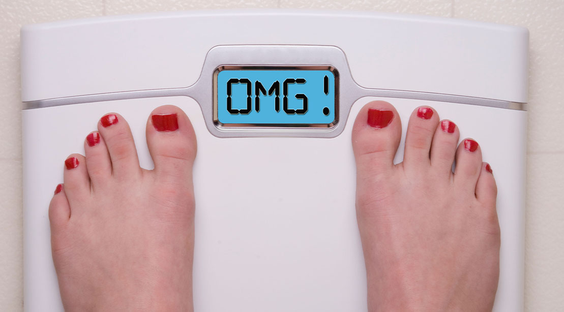 Woman with painted toe nails noticing a weight gain on the scale that says OMG